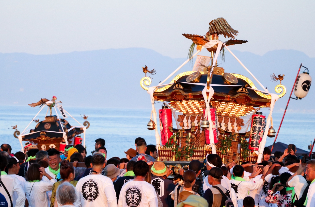 明け方の陽光の中、波しぶきを浴びながら進むお神輿